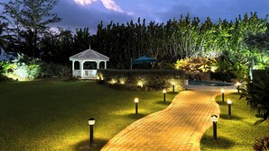 A gazebo with a white roof and lattice front, surrounded by well-lit hedges and a paved pathway leading to it. - The Lauren Taylor Villa - Tobago


 (Lowlands)