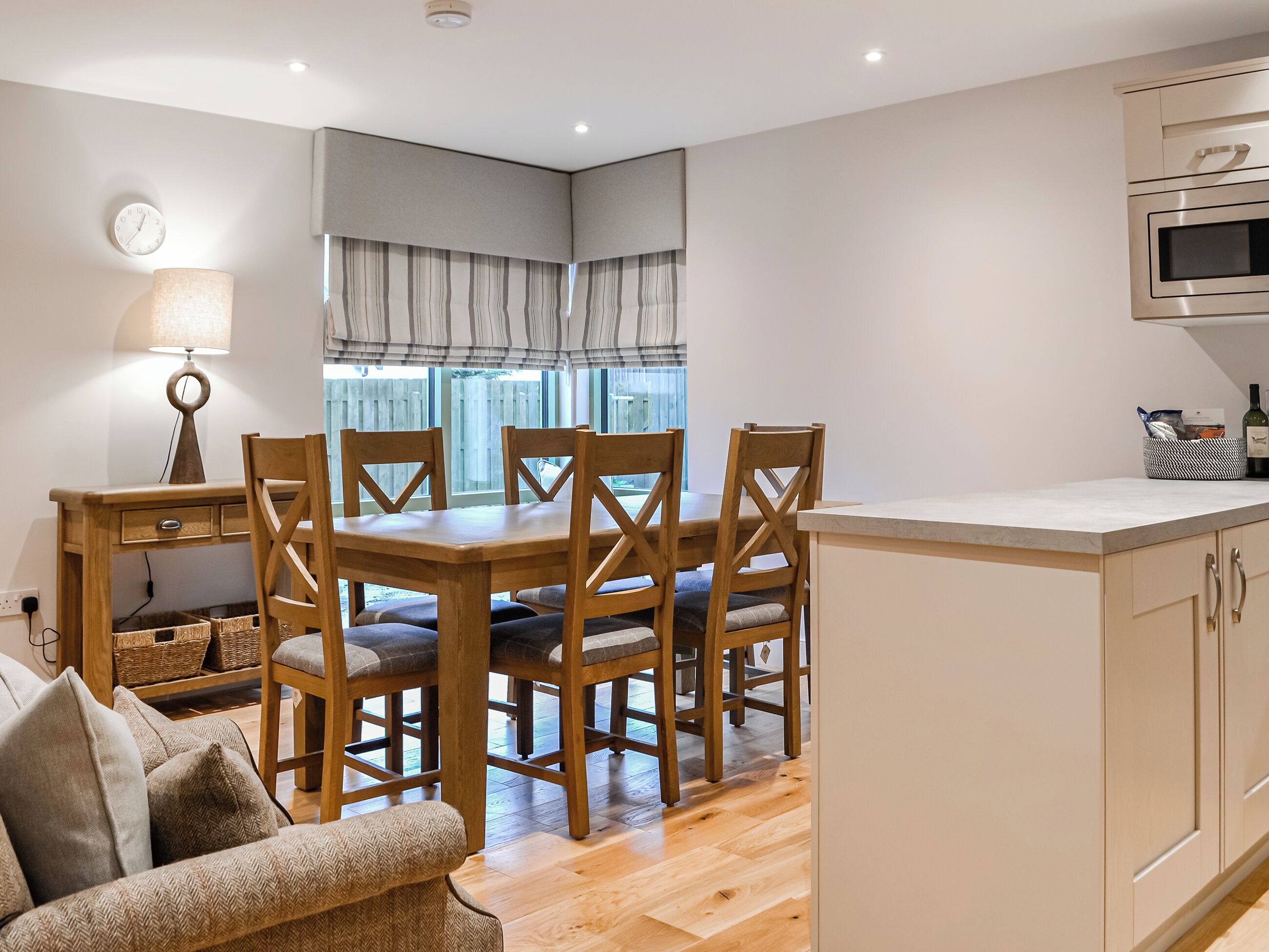 A modern kitchen with wooden cabinets, a built-in microwave, and a dining area with a wooden table and chairs.