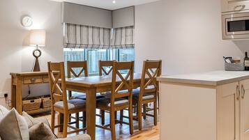 A modern kitchen with wooden cabinets, a built-in microwave, and a dining area with a wooden table and chairs.