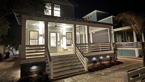 A two-story house with a covered porch and a staircase leading to the upper level. - Tigh Na Mara is a Porch Lover’s Paradise in Orange Beach, AL (Orange Beach)