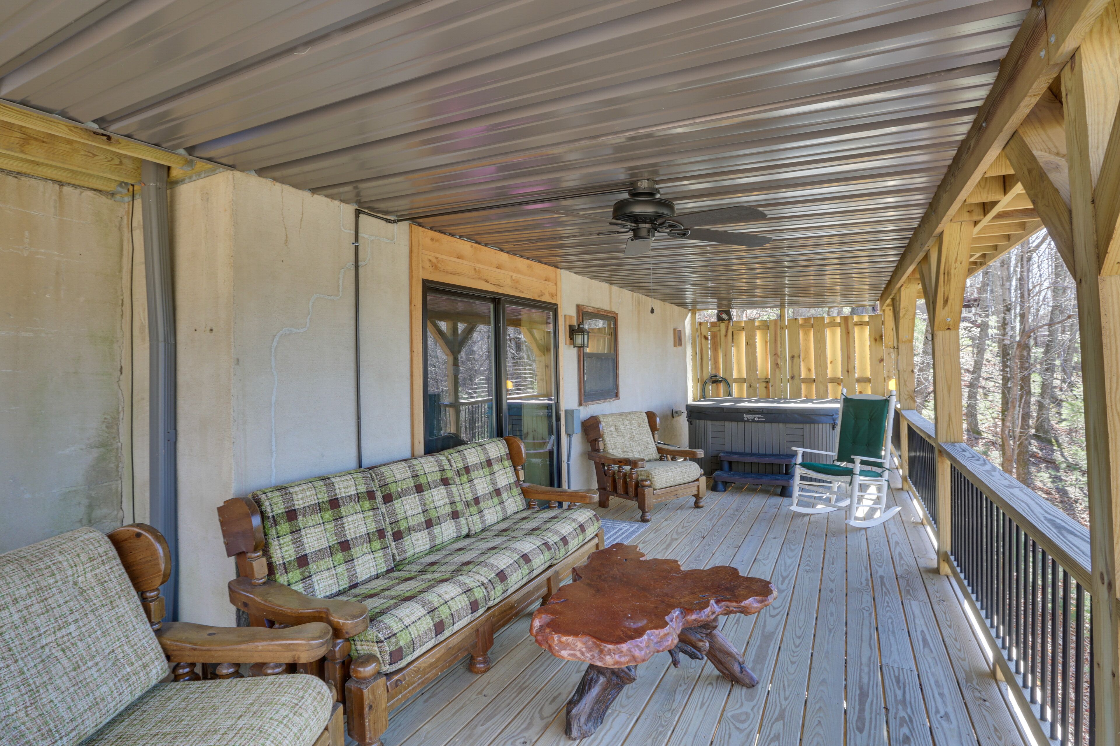 A covered porch with a wooden bench, a plaid sofa, and a rocking chair.