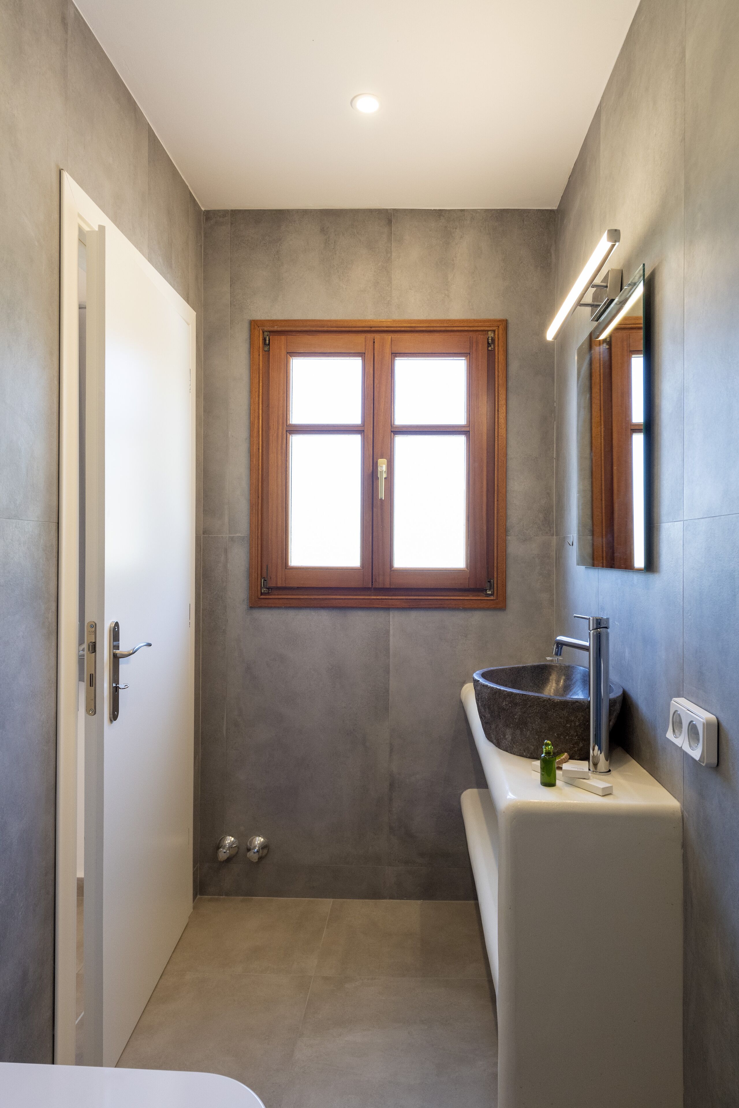A modern bathroom with a large window, a sink, and a mirror.
