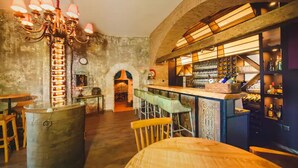 A bar area with a rustic stone wall, wooden bar stools, and a chandelier. - Amadeus Apartments in Caesar Resort&Spa,Long Beach.
 (Nicosia)