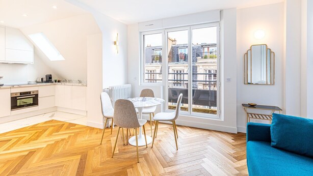 A modern apartment with a kitchen, dining area, and a balcony with a city view.