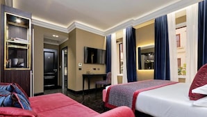 Ein Hotelzimmer mit zwei Betten, einem Schreibtisch, einem Fernseher und einer Minibar.