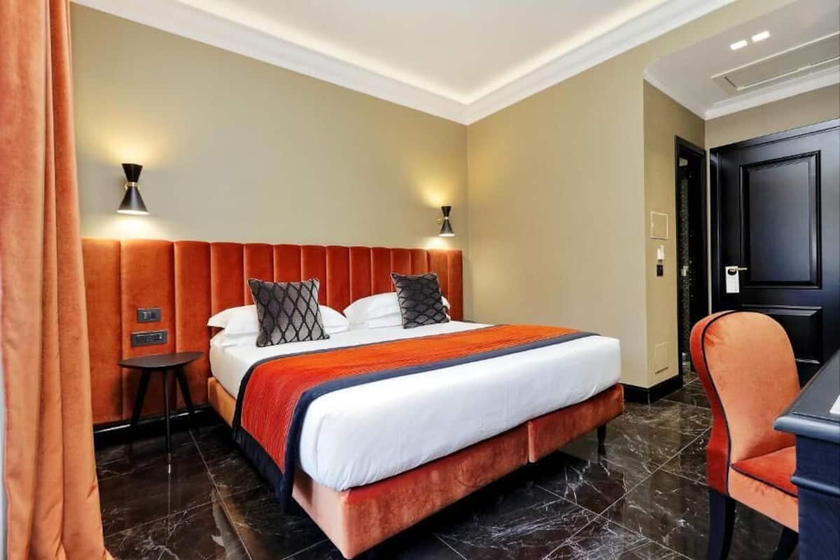 Habitación de hotel con una cama grande, dos lámparas de noche, un escritorio y una silla.