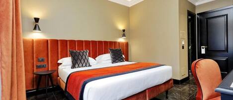A hotel room with a large bed, two bedside lamps, a desk, and a chair.