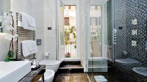 Ein modernes Badezimmer mit einer Duschkabine aus Glas, einer weißen Badewanne und einer Marmorarbeitsplatte.
