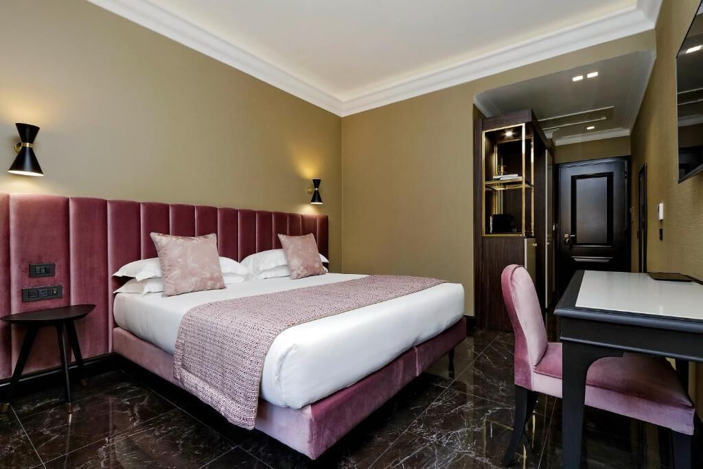 Quarto de hotel com uma cama grande, uma escrivaninha e uma cadeira.