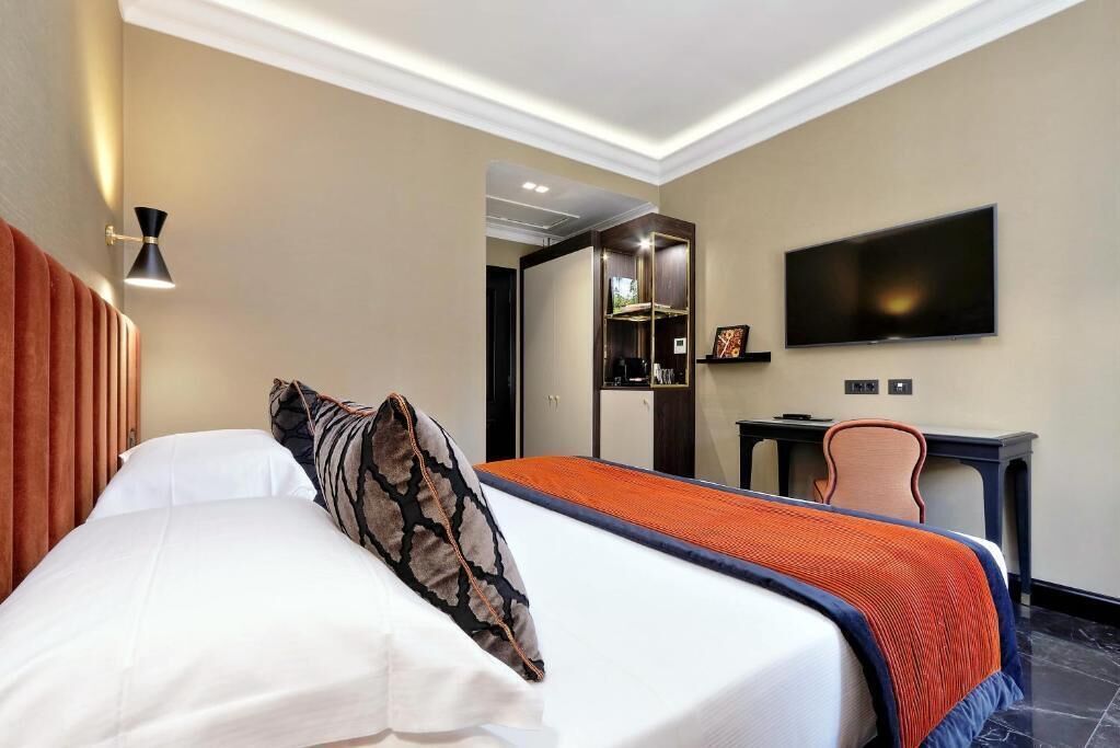 A hotel room with a bed, a desk, a television, and a mirror.