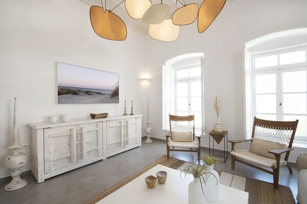 A spacious living room with a white cabinet, a large painting, and a wooden chair.