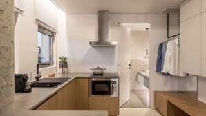 A modern kitchen with a built-in oven, a coffee machine, and a window overlooking the room. - Arca A1 Junior Suite (Athens)