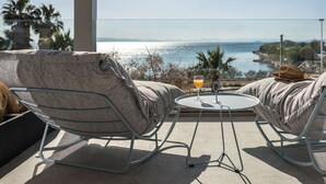 A balcony with two rocking chairs, a small round table, and a glass of orange juice. - Arca A1 Junior Suite (Athens)