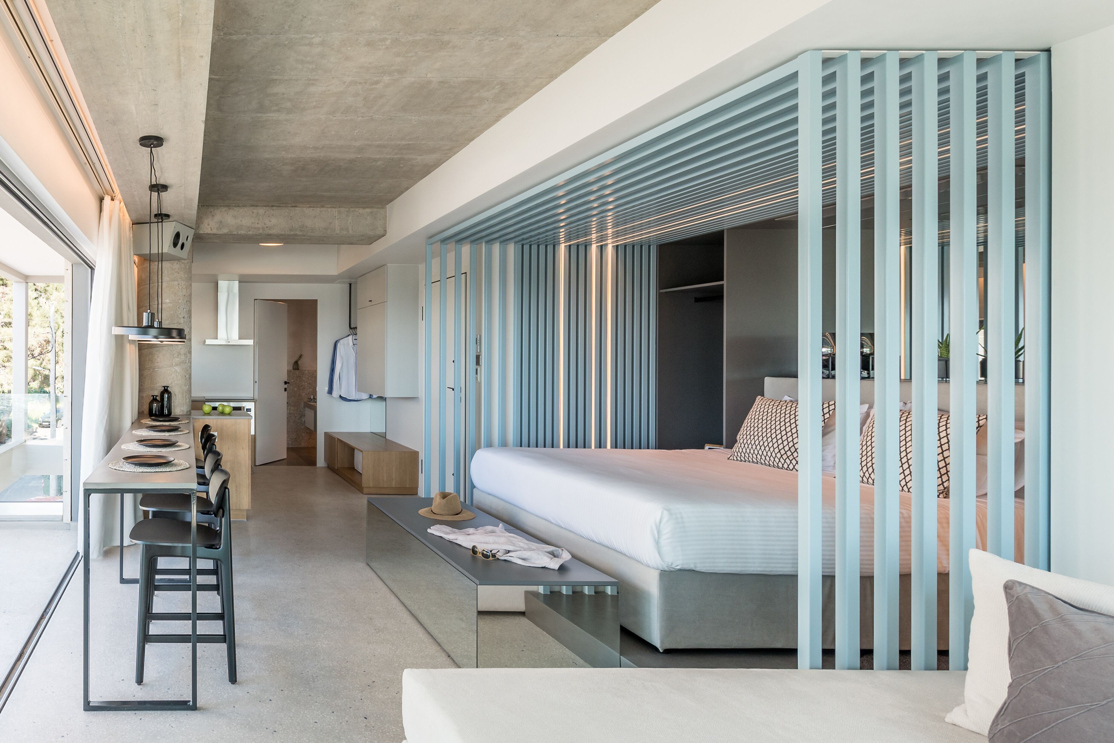 Une chambre à coucher moderne avec un lit, des tables de chevet et une vue sur la cuisine.