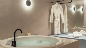 Un baño moderno con una bañera grande, un perchero con batas y un espejo.