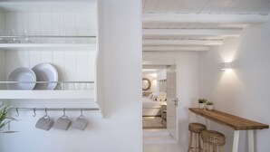A kitchen with white cabinetry, a hanging pot rack, and a wooden bar with stools.