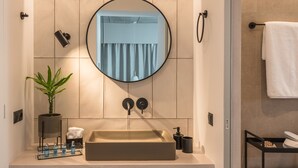 A modern bathroom with a large round mirror, a beige sink, and a wooden shelf. - Mytilus A3 Deluxe Apartment (Athens)