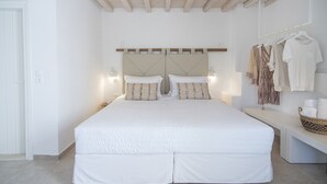 Ein Schlafzimmer mit einem großen Bett, Nachttischen, einer Bank und einem Kleiderständer.