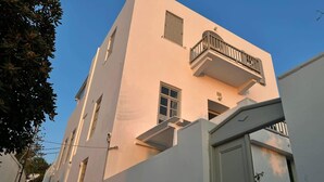 Ein mehrgeschossiges Gebäude mit einem Balkon im zweiten Stock, einer Tür im Erdgeschoss und einem kleinen Fenster im dritten Stock.