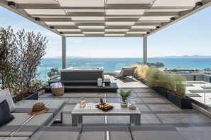 A rooftop terrace with a pool, lounge chairs, a table with drinks and fruit, and a view of the ocean. - Ensis D1 Penthouse Suite (Athens)