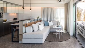 A modern living space with a sofa, a small table, and a kitchen area.
