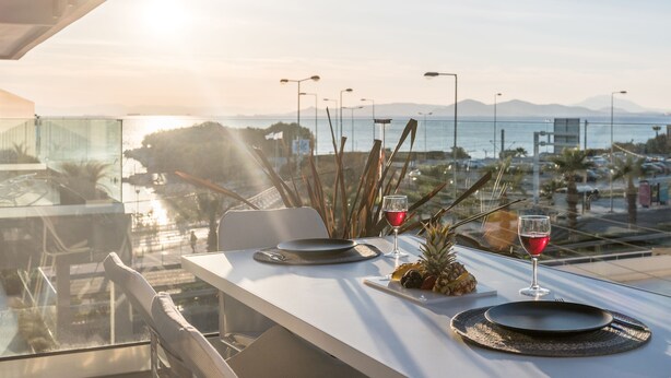 A table set for two with a view of the sea and mountains.