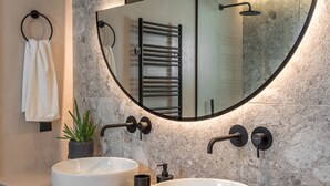 A modern bathroom with two round white sinks, a large mirror, and a towel rack.