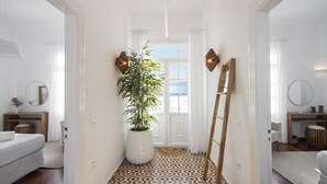 A hallway with a patterned floor, a large potted plant, and a wooden ladder leaning against the wall. - Pietra Bianca 1891 Junior Suite (Mykonos)