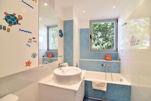 Enjoy a refreshing bathroom experience with a large sink, bathtub, and showerhead, surrounded by playful sea creature decals.