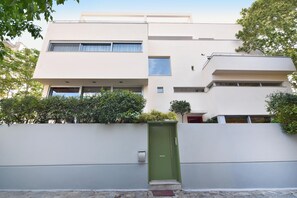 Stylish two-story building with a flat facade and rectangular windows, featuring a prominent entrance and a small step leading up to it.