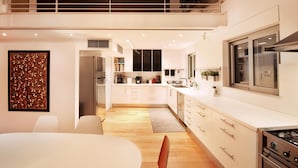 Una cocina moderna con armarios blancos, electrodomésticos de acero inoxidable y piso de madera.