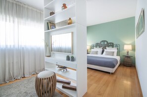 Relax in a serene bedroom with a large bed, bedside table, and wall-mounted shelf.