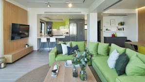 Een moderne woonkamer met een groene bank, een bijzettafeltje en een flatscreen televisie.