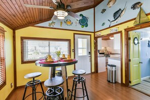 A kitchen with wooden floors, a round table with stools, and a ceiling fan.