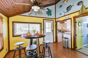 A kitchen with wooden floors, a round table with stools, and a ceiling fan.