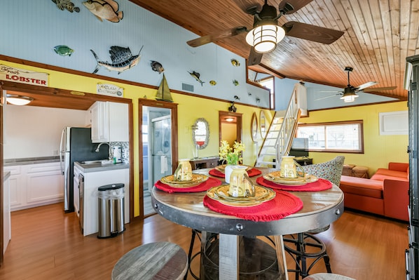 A dining area with a round table, chairs, and a ceiling fan.
