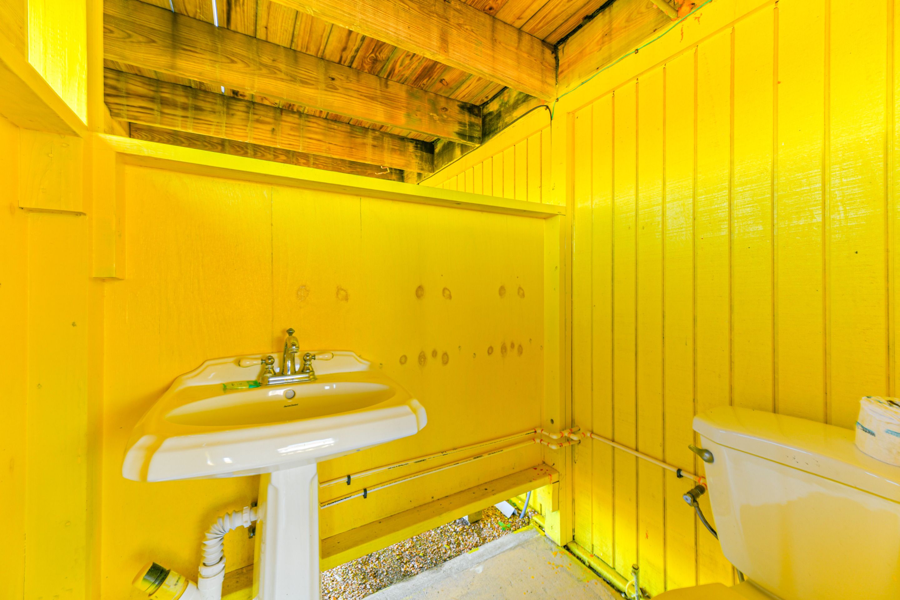 A bathroom with yellow walls, a white sink, and a toilet.
