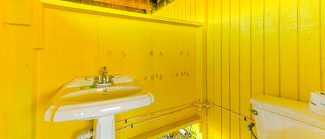 A bathroom with yellow walls, a white sink, and a toilet.
