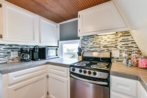 A modern kitchen with white cabinets, a stainless steel stove, and a coffee maker.