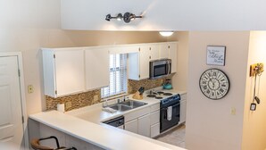 A modern kitchen with white cabinets, a microwave, stove, and a clock on the wall. - Conveniently located with great views, but close to all the action! (Branson)