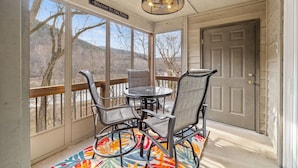 A covered porch with a table and chairs, a sign reading "Welcome to our porch", and a view of trees and hills. - Conveniently located with great views, but close to all the action! (Branson)