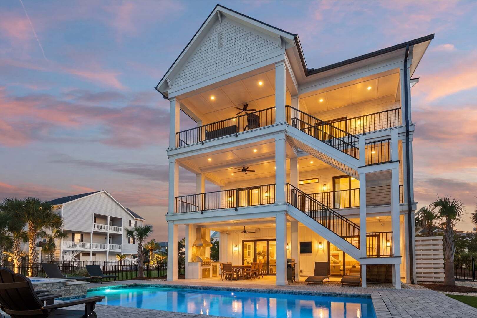 A multi-story house with a pool, balconies, and outdoor lighting.