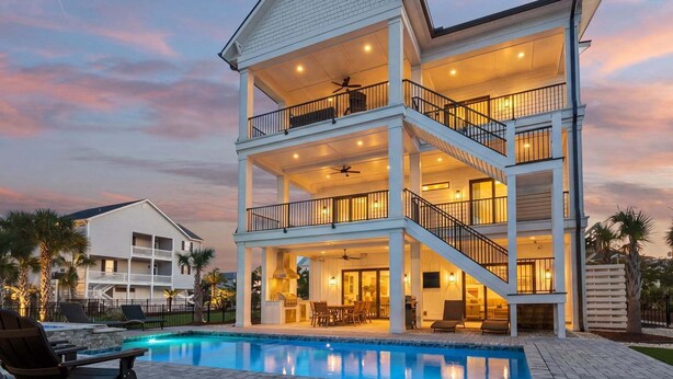 Ein mehrstöckiges Haus mit Pool, Balkonen und Außenbeleuchtung.