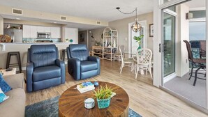 A modern living room with leather sofas, a wooden coffee table, and a dining area with white chairs. - Ocean view unit with an range of aquatic activities! (North Myrtle Beach)