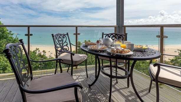 Ein Balkon mit Frühstückstisch mit Blick auf einen Strand.