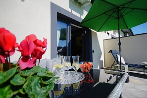 An outdoor seating area with a table set for two, a green umbrella, and a chair. - Holiday homes with terraces, Mielenko (Mielenko)