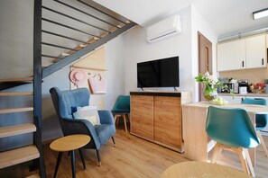 A modern living space with a staircase, a flat-screen TV, a wooden cabinet, and a dining area with chairs. - Holiday homes with terraces, Mielenko (Mielenko)