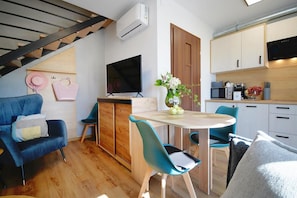 A modern living space with a sofa, a dining table, chairs, a TV, a kitchen area, and a staircase. - Holiday homes with terraces, Mielenko (Mielenko)