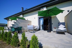 A patio area with outdoor seating, a covered table, and a green umbrella. - Holiday homes with terraces, Mielenko (Mielenko)