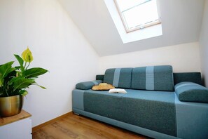 A room with a blue sofa, a potted plant, and a skylight. - Holiday homes with terraces, Mielenko (Mielenko)